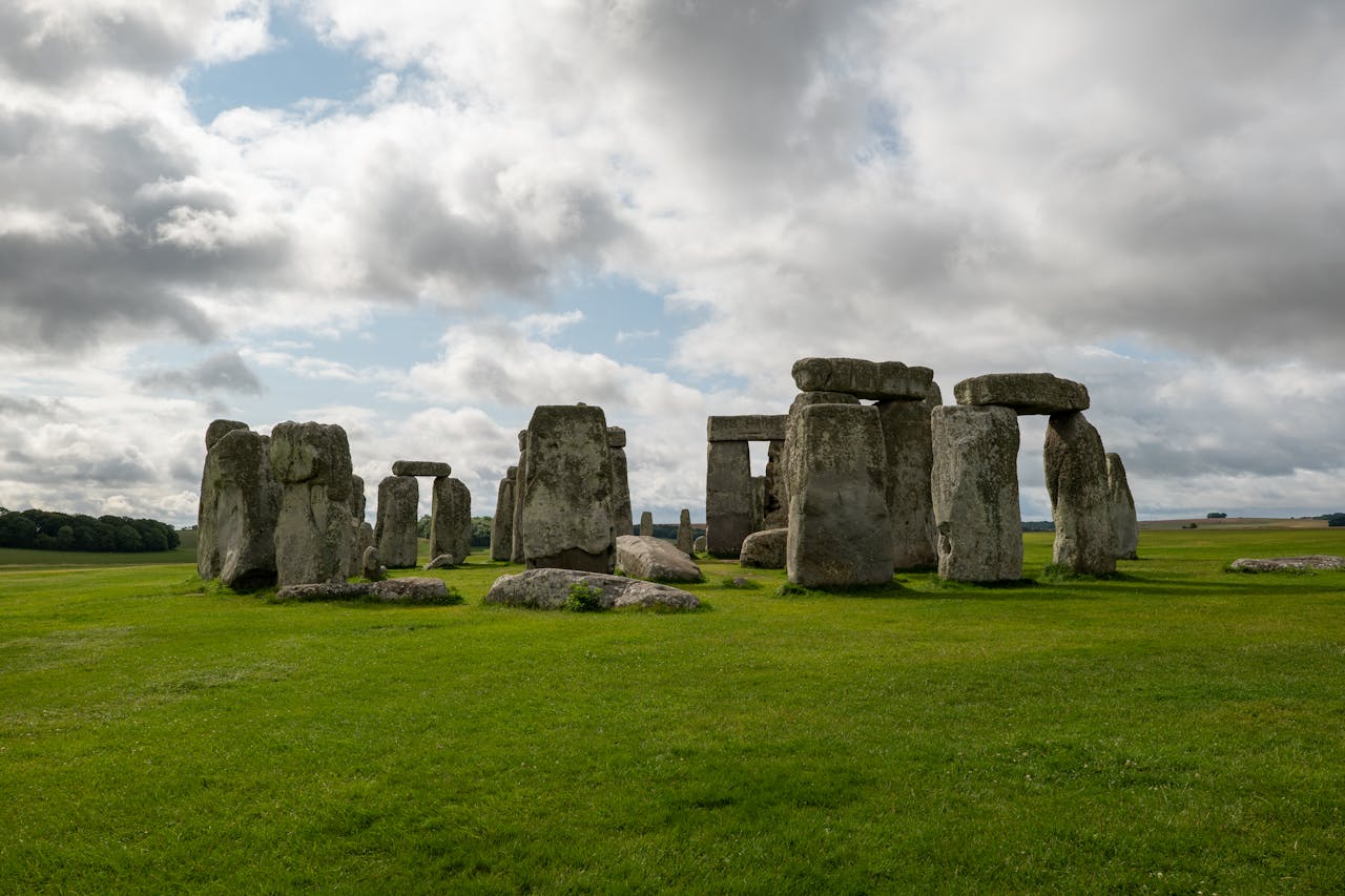 A historic view of Stonehenge with dramatic clouds and green fields, showcasing British heritage.