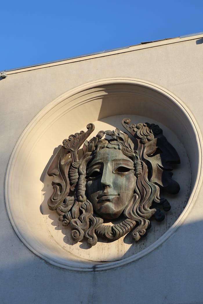 Intricate Medusa face sculpture on building during daylight.
