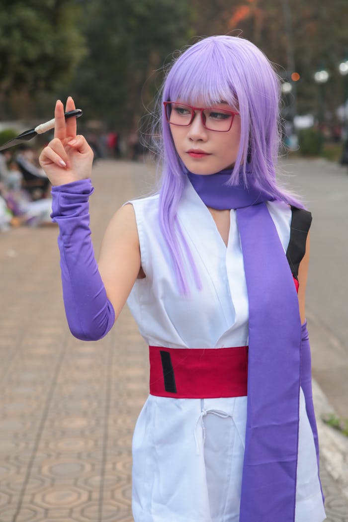 A young woman in anime cosplay, wearing a purple wig and glasses, poses outdoors.