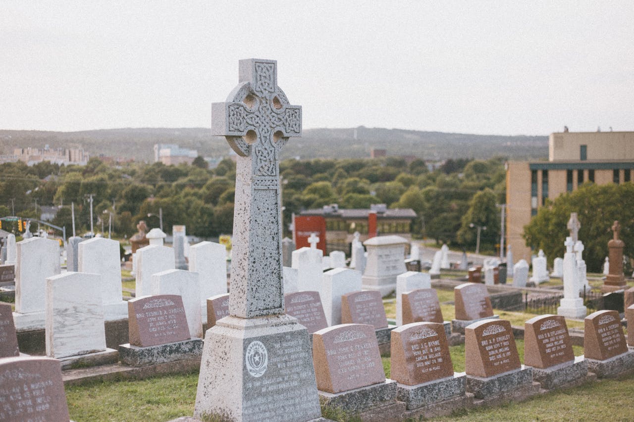 Peaceful cemetery view showcasing a prominent Celtic cross tombstone surrounded by gravestones.